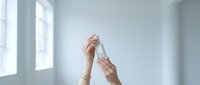 Female hands holding white pregnancy test in bright modern interior with natural window light for healthcare and family planning concepts.