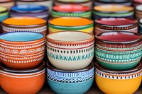 Colorful ceramic bowls with ethnic patterns and geometric ornaments stacked together. Traditional handcrafted pottery with tribal decorative elements in vibrant colors.