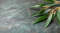 Green bamboo leaves and golden branches on dark marble texture background, natural zen composition for spa and wellness design.