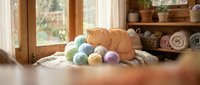Cozy home spa setup with colorful bath bombs, orange towel and natural wooden shelving creating relaxing wellness atmosphere for self-care routine.