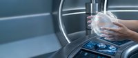 Close-up of hands holding transparent globe over futuristic car dashboard with digital controls and holographic interface for automotive technology and innovation concepts.