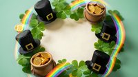 Leprechaun hats, gold coins, and shamrock clovers arranged in circle with rainbow on mint background, St. Patrick's Day celebration theme with copy space.