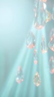 Hanging crystal prisms and gemstones casting colorful light reflections on soft turquoise background, creating elegant bokeh effect for luxury, jewelry, and design projects.