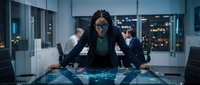 African American businesswoman with dreadlocks analyzing holographic data display in modern corporate office with colleagues during evening meeting.