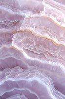 Ethereal purple agate crystal macro showing delicate layered patterns and natural formations with golden veining, creating an abstract geological background.
