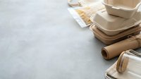 Eco-friendly disposable tableware made from sustainable materials including bamboo plates, paper cups and biodegradable containers on gray background.