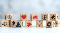Wooden blocks with healthcare and wellness symbols including medical cross, heart, brain, scales of justice, meditation figure, and lightbulb on white background.