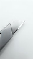Close-up of a silver utility knife with a sharp retractable blade on a white background, used in construction, crafts, and DIY projects.