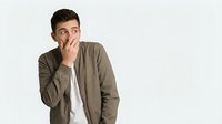 Young man with dark hair and olive skin tone wearing olive green jacket over white shirt, hand near mouth expressing worry, concern, or thoughtful contemplation against white background.