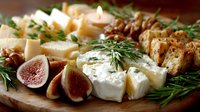 Gourmet cheese platter with fresh figs, nuts and herbs on wooden board for entertaining and appetizer presentations.