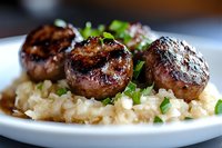 Grilled mushrooms with herbs served on creamy risotto rice, garnished with fresh parsley on white plate, close up view of gourmet vegetarian meal.