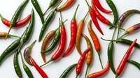 Colorful hot chili peppers scattered on white background. Fresh spicy vegetables in red, green and orange colors for cooking and culinary projects.