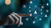 Finger pointing at glowing social network visualization with connected user icons on dark turquoise background, illustrating digital networking concept.