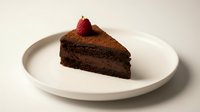 Slice of rich chocolate cake topped with fresh strawberry on white plate, suitable for bakery menus, dessert blogs, and food photography collections.