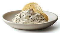 Creamy whipped ricotta cheese topped with black pepper, olive oil, and crispy parmesan tuile served on minimalist ceramic plate. Food photography.