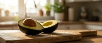 Fresh ripe avocado halves on wooden cutting board in modern kitchen with natural sunlight streaming through window creating warm atmosphere for cooking.