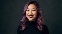 Young Asian woman with purple hair smiling confidently in black turtleneck against dark background for professional headshot and portrait photography.