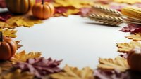 Autumn frame with colorful fall leaves, pumpkins and wheat stalks surrounding blank white paper space for seasonal text or design projects.