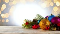 Festive Christmas ornaments with pine branches on wooden surface against golden bokeh background for holiday greeting cards.