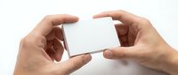 Hands holding blank white business card mockup on clean background for branding and corporate identity design projects.
