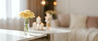 Fresh yellow roses in glass vase on white table creating elegant home decor atmosphere with soft natural lighting and cozy living room background.