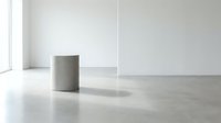Minimalist interior space with concrete cylindrical column, polished concrete floor, and white walls with natural light from window.