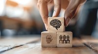 Wooden blocks with brain, hand and people icons symbolizing teamwork, leadership and cognitive skills arranged in business concept composition.