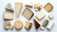 Assorted gourmet cheese selection featuring blue cheese, brie, cheddar, goat cheese and aged varieties arranged on white background for culinary design.