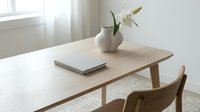Minimalist wooden dining table with white lily in ceramic vase and closed book, modern Scandinavian interior design for home decor and lifestyle concepts.