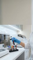 Laboratory technician in protective gloves holding blood sample test tube in modern medical research facility for clinical analysis and diagnostics.