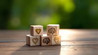 Wooden blocks with heart and brain icons symbolizing emotional and intellectual intelligence on rustic table with blurred green background.