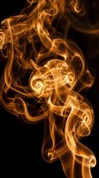 Golden orange smoke swirls dancing against black background creating abstract flowing patterns with luminous ethereal wisps and curving trails.