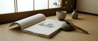 Handmade paper book with hello calligraphy on tatami floor in a serene Japanese-style room with ceramic decor and natural light.