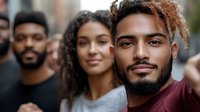 Young diverse friends smiling and looking at camera outdoors in urban setting, featuring natural curly hair and casual style, expressing joy and unity.