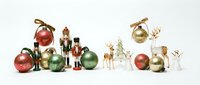 Festive Christmas ornaments and decorative figurines arranged on white background including colorful baubles, nutcrackers, reindeer and holiday decor elements.
