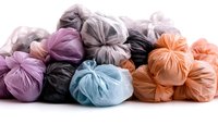 Colorful tied garbage bags in pastel shades of purple, blue, orange and gray arranged in artistic composition on white background. Isolated for design use.