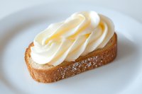 Toasted bread slice topped with swirled whipped cream on a white plate, a delicious dessert or breakfast treat for food blogs.