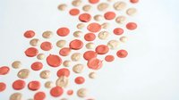 Scattered round confetti pieces in coral pink and gold tones on white background for party decorations and celebration designs.
