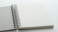 Open spiral-bound notebook with blank white pages and gray cover on white background, ready for writing, sketching, and creative projects.