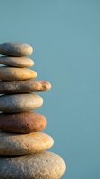 Balanced stack of smooth river stones creating zen tower against calming blue background for meditation and wellness concepts.