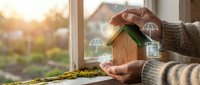 Hands holding wooden birdhouse with glowing green house icons, symbolizing eco-friendly living and sustainable home energy solutions for environmental conservation campaigns.