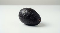 Fresh ripe avocado with dark textured skin isolated on white background, ready for food and culinary design projects.