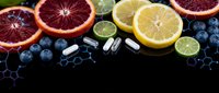 Fresh citrus fruits and blueberries with vitamin supplements on dark background. Healthy nutrition concept with natural antioxidants and dietary pills.