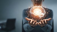 Businessman holding glowing brain hologram with sparkling lights representing artificial intelligence, innovation and creative thinking in modern office.