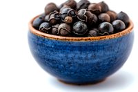 Roasted coffee beans in handcrafted blue ceramic bowl against white background. Close-up view shows rich dark brown color and textured surface of fresh beans.