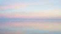 Serene dawn seascape with soft pastel pink, blue, and cream tones reflecting across calm water. Minimalist coastal scene for wellness, travel, and lifestyle design projects.