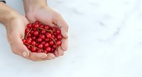 Male hands holding fresh red currants on white marble background, suitable for food photography, culinary content, and healthy eating concepts.