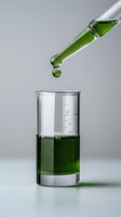Green liquid droplet falling from glass dropper into measuring beaker containing emerald solution against light gray background, capturing moment of scientific experiment.