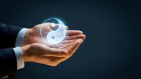 Businessman holding glowing yin yang symbol in cupped hands against dark background, representing balance, harmony, duality, and spiritual wellness concepts for business and meditation.