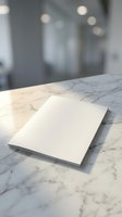 Blank white paper sheets on marble surface with soft lighting and blurred office background for business presentations and corporate communications.